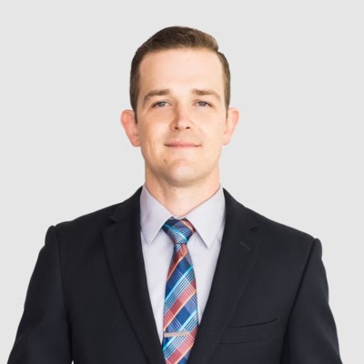 Michael Ruttle, Partner and Chair of Immigration & Global Mobility at Omnus Law, wearing a dark suit and multicolored tie against a light background.